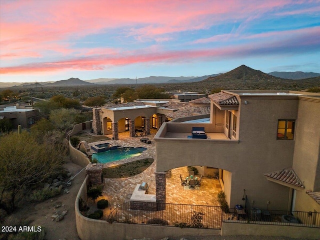 exterior space with an in ground hot tub, a mountain view, and a patio