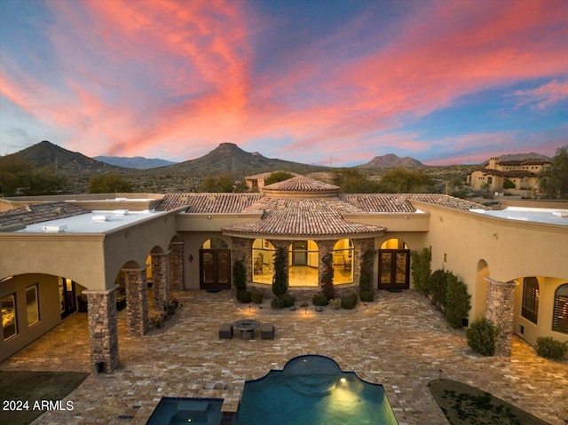 back house at dusk featuring a mountain view and a patio