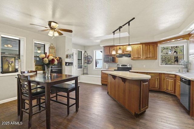 kitchen with a kitchen island, dark wood-style flooring, stainless steel appliances, light countertops, and under cabinet range hood