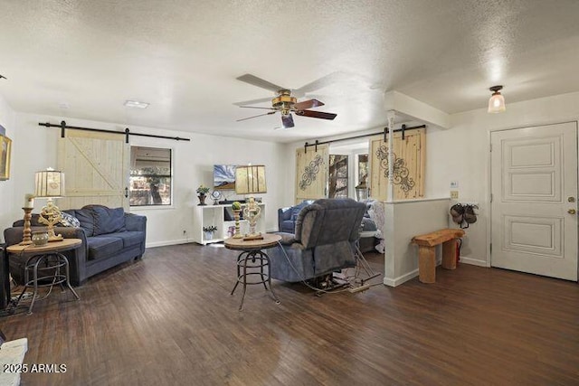 living room featuring a barn door, a textured ceiling, ceiling fan, and wood finished floors