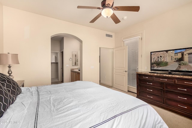 carpeted bedroom with arched walkways, ceiling fan, a sink, a closet, and connected bathroom