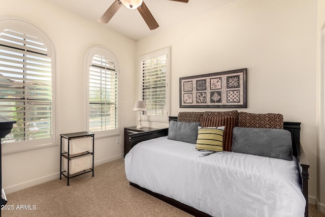 carpeted bedroom featuring multiple windows, baseboards, and a ceiling fan