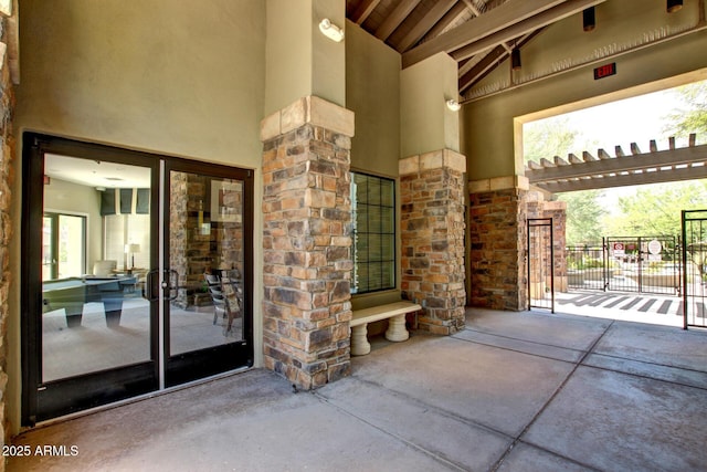 entrance to property with stone siding, stucco siding, fence, and a gate