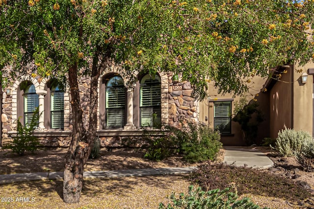 view of front facade featuring stucco siding and stone siding