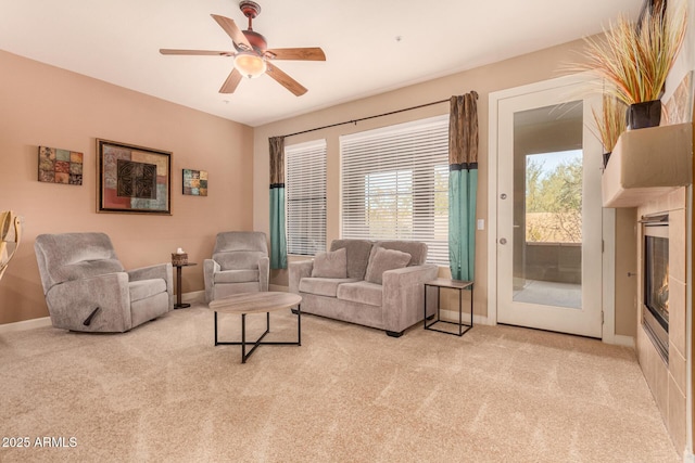 living room with carpet, baseboards, a glass covered fireplace, and a ceiling fan