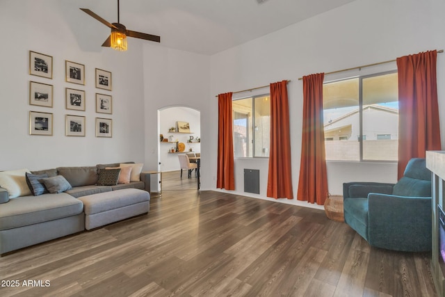 living room with ceiling fan, a towering ceiling, and wood-type flooring