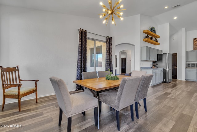 dining room featuring a notable chandelier, light hardwood / wood-style flooring, and high vaulted ceiling