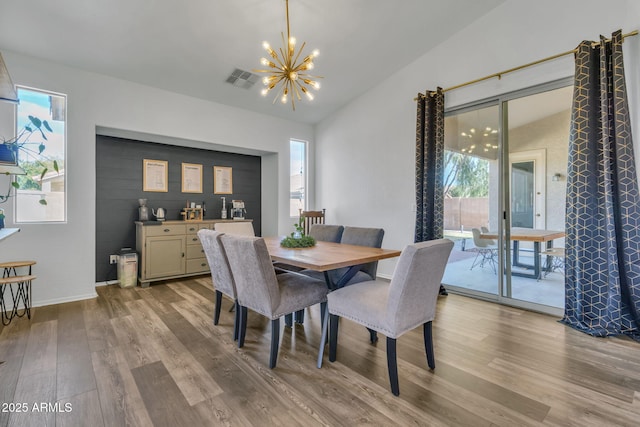 dining space featuring an inviting chandelier, lofted ceiling, and light wood-type flooring