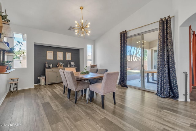 dining area featuring vaulted ceiling, an inviting chandelier, and light hardwood / wood-style floors