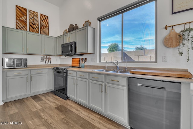 kitchen with sink, light hardwood / wood-style flooring, and black appliances