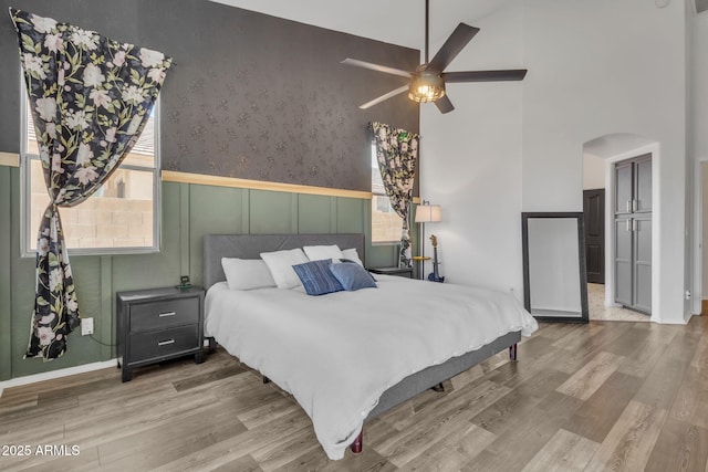 bedroom featuring a high ceiling, ceiling fan, and light hardwood / wood-style flooring