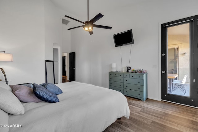 bedroom with wood-type flooring, high vaulted ceiling, and ceiling fan