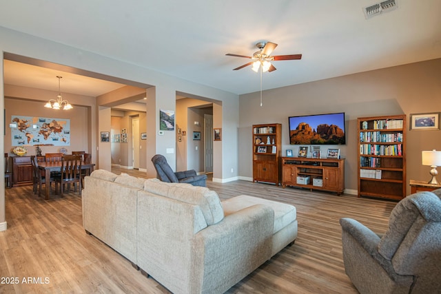 living room featuring wood-type flooring and ceiling fan with notable chandelier