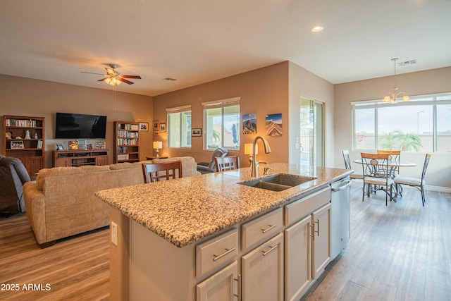 kitchen featuring pendant lighting, sink, white cabinetry, an island with sink, and stainless steel dishwasher