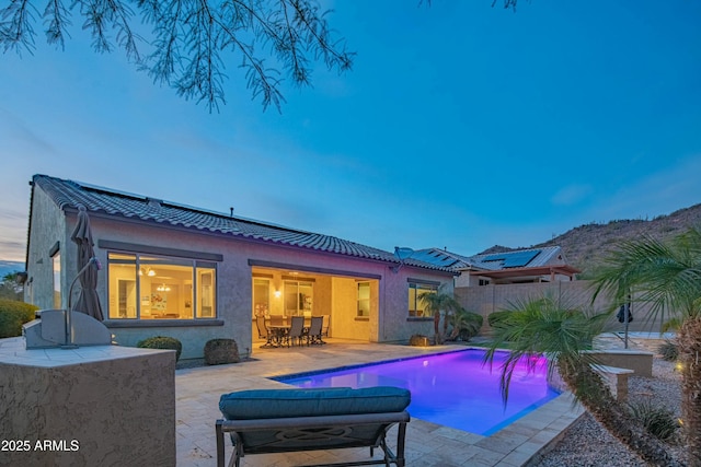 pool at dusk with a patio area