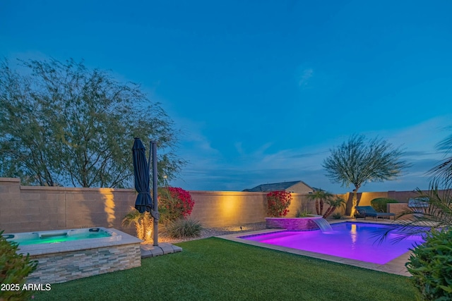 pool at dusk with an in ground hot tub, pool water feature, and a lawn