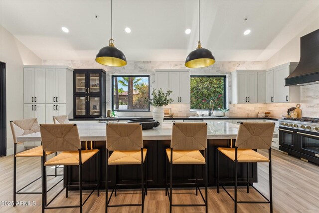 kitchen featuring range with two ovens, pendant lighting, a sink, and custom exhaust hood