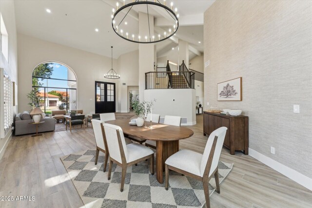 dining room featuring a chandelier, an accent wall, baseboards, and light wood-style floors