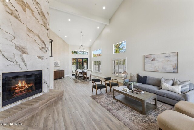 living room featuring vaulted ceiling with beams, light wood finished floors, a premium fireplace, and recessed lighting