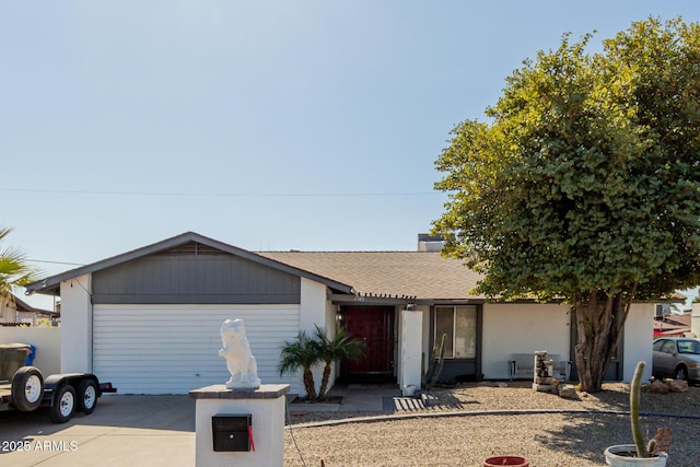 ranch-style house featuring concrete driveway, a shingled roof, and an attached garage