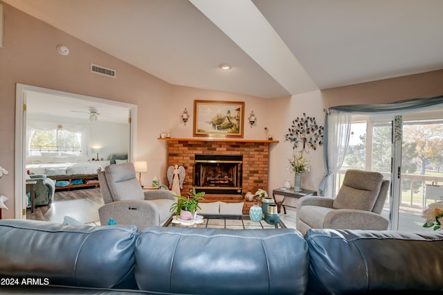 living room with hardwood / wood-style flooring, a brick fireplace, ceiling fan, and lofted ceiling