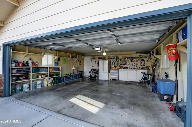 garage featuring a workshop area, white refrigerator, and a garage door opener