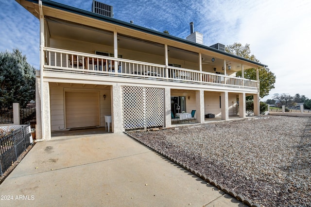 rear view of property featuring a garage, a balcony, and cooling unit