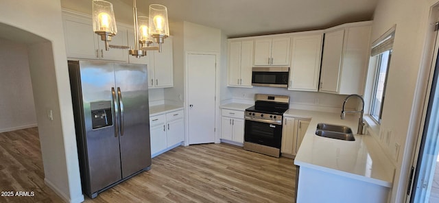 kitchen with a sink, light wood-style flooring, appliances with stainless steel finishes, and white cabinetry