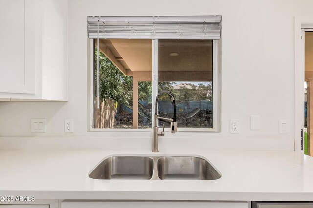 details featuring a sink, white cabinets, and light countertops