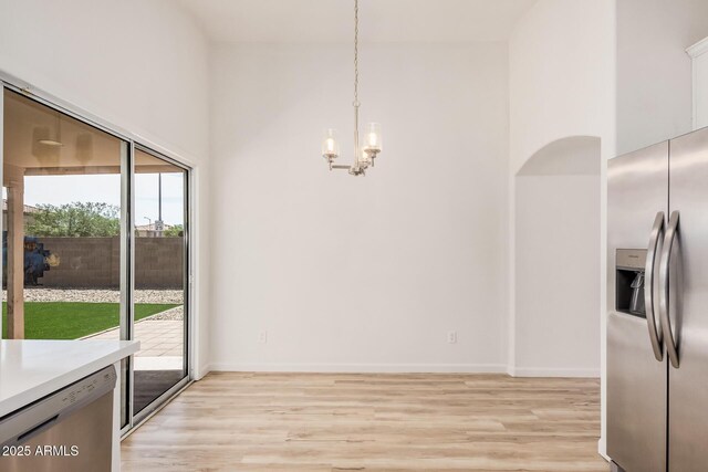 unfurnished dining area with an inviting chandelier, light wood-style flooring, and baseboards