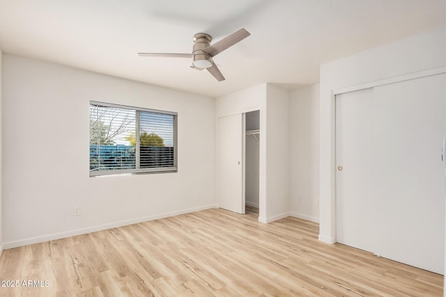 unfurnished bedroom with baseboards, ceiling fan, two closets, and wood finished floors