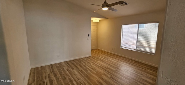 spare room featuring ceiling fan, baseboards, wood finished floors, vaulted ceiling, and visible vents