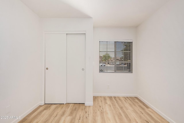 unfurnished bedroom featuring baseboards, a closet, and wood finished floors