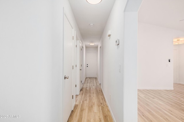 corridor with baseboards and light wood-type flooring