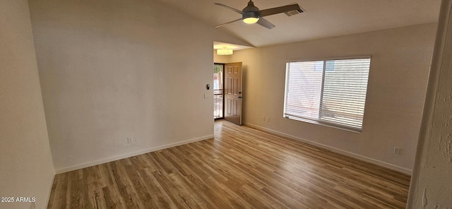 spare room featuring visible vents, wood finished floors, lofted ceiling, baseboards, and ceiling fan