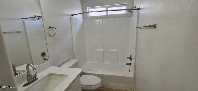 bathroom with toilet, a textured wall, shower / bath combination, and vanity
