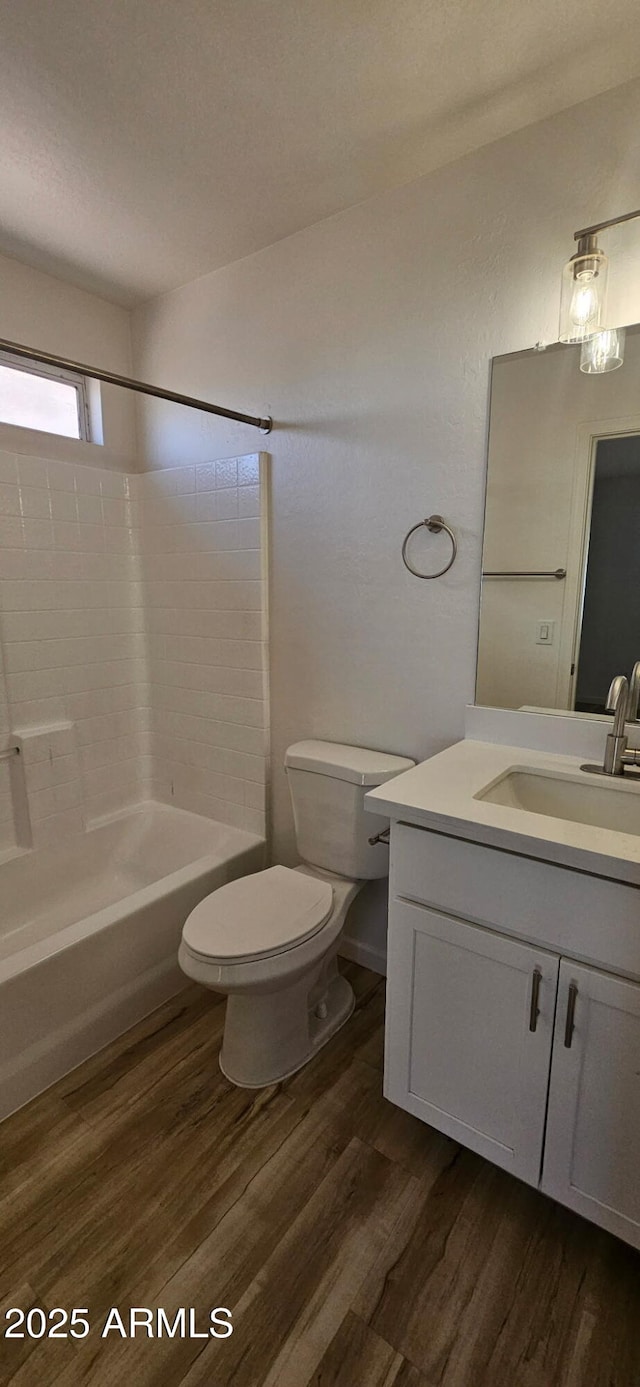 bathroom featuring shower / bathtub combination, toilet, wood finished floors, and vanity