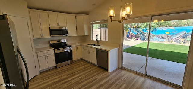 kitchen with wood finished floors, a sink, light countertops, stainless steel appliances, and white cabinetry