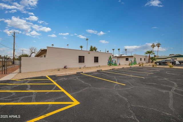 uncovered parking lot featuring a gate and fence