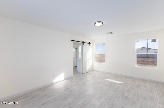 empty room with a barn door and light wood-type flooring