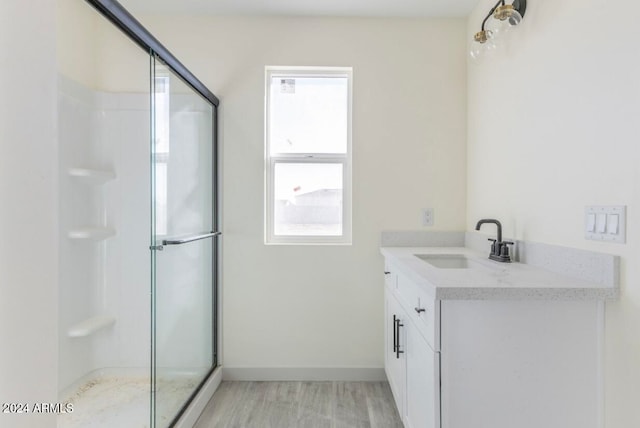 bathroom featuring hardwood / wood-style floors, plenty of natural light, a shower with shower door, and vanity