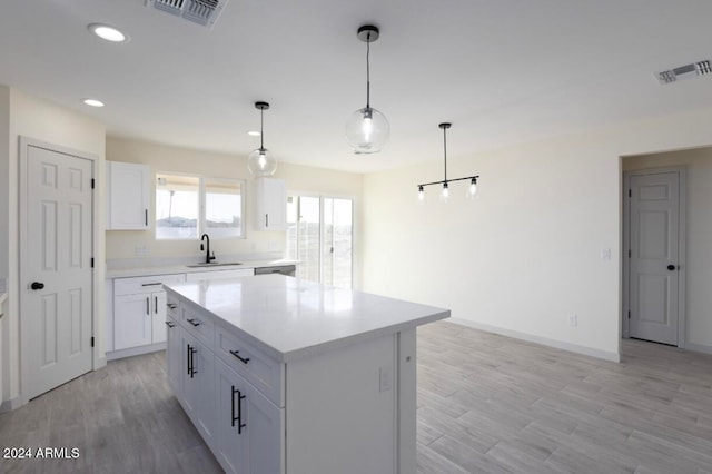 kitchen with pendant lighting, a center island, light hardwood / wood-style floors, and white cabinetry