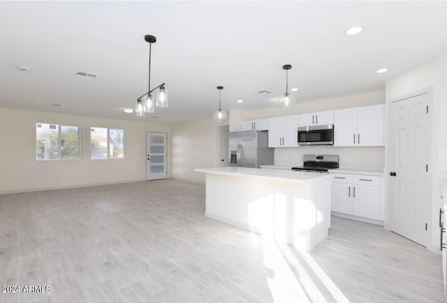 kitchen featuring pendant lighting, light wood-type flooring, appliances with stainless steel finishes, a kitchen island, and white cabinetry