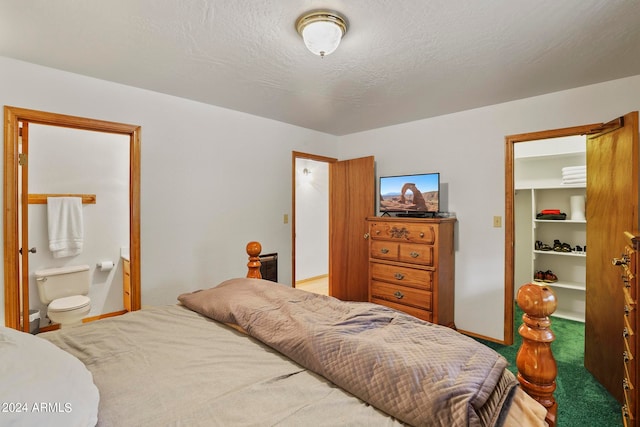 bedroom with a textured ceiling, connected bathroom, and carpet floors