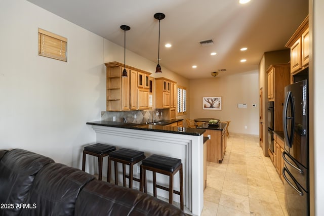 kitchen featuring decorative light fixtures, refrigerator, kitchen peninsula, and sink