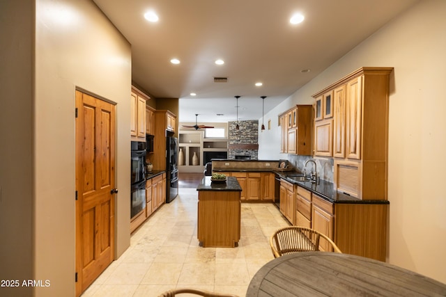 kitchen featuring ceiling fan, sink, hanging light fixtures, a kitchen island, and black appliances