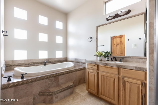 bathroom featuring tiled tub and vanity