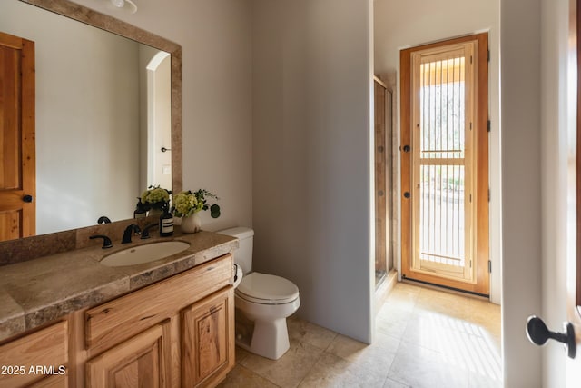 bathroom featuring tile patterned flooring, vanity, toilet, and a shower with door