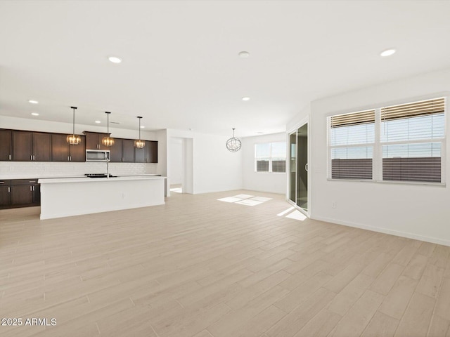 unfurnished living room featuring light wood-type flooring and an inviting chandelier