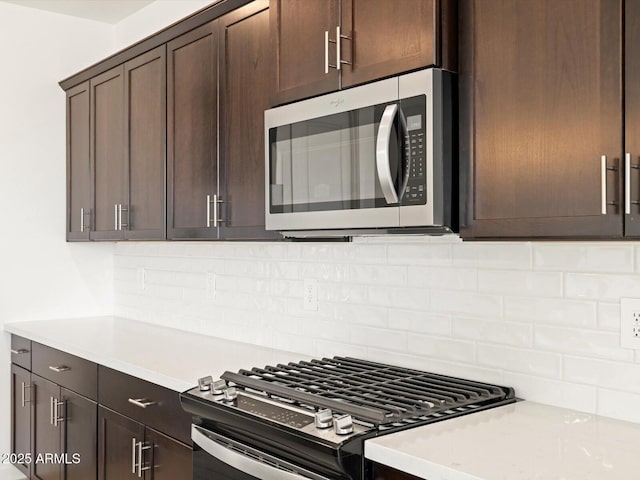 kitchen with appliances with stainless steel finishes, light stone counters, decorative backsplash, and dark brown cabinetry